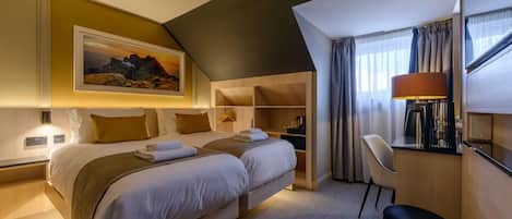 A hotel room with a bed, bedside tables, a desk, a chair, a lamp, and a painting on the wall.