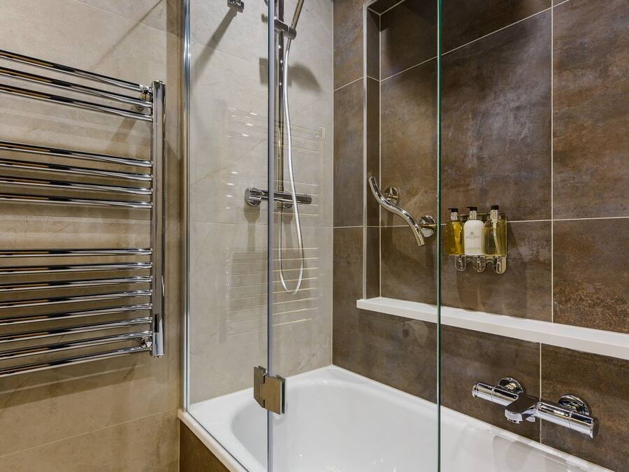 Un baño moderno con ducha envuelta en vidrio, una bañera blanca y un perchero para toallas.