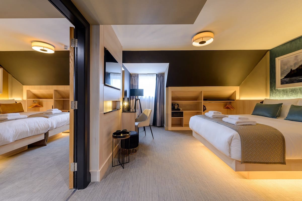 A hotel room with two beds, a desk, a chair, and a wardrobe.