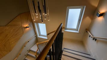 A modern staircase with wooden steps, black handrails, and pendant lighting.