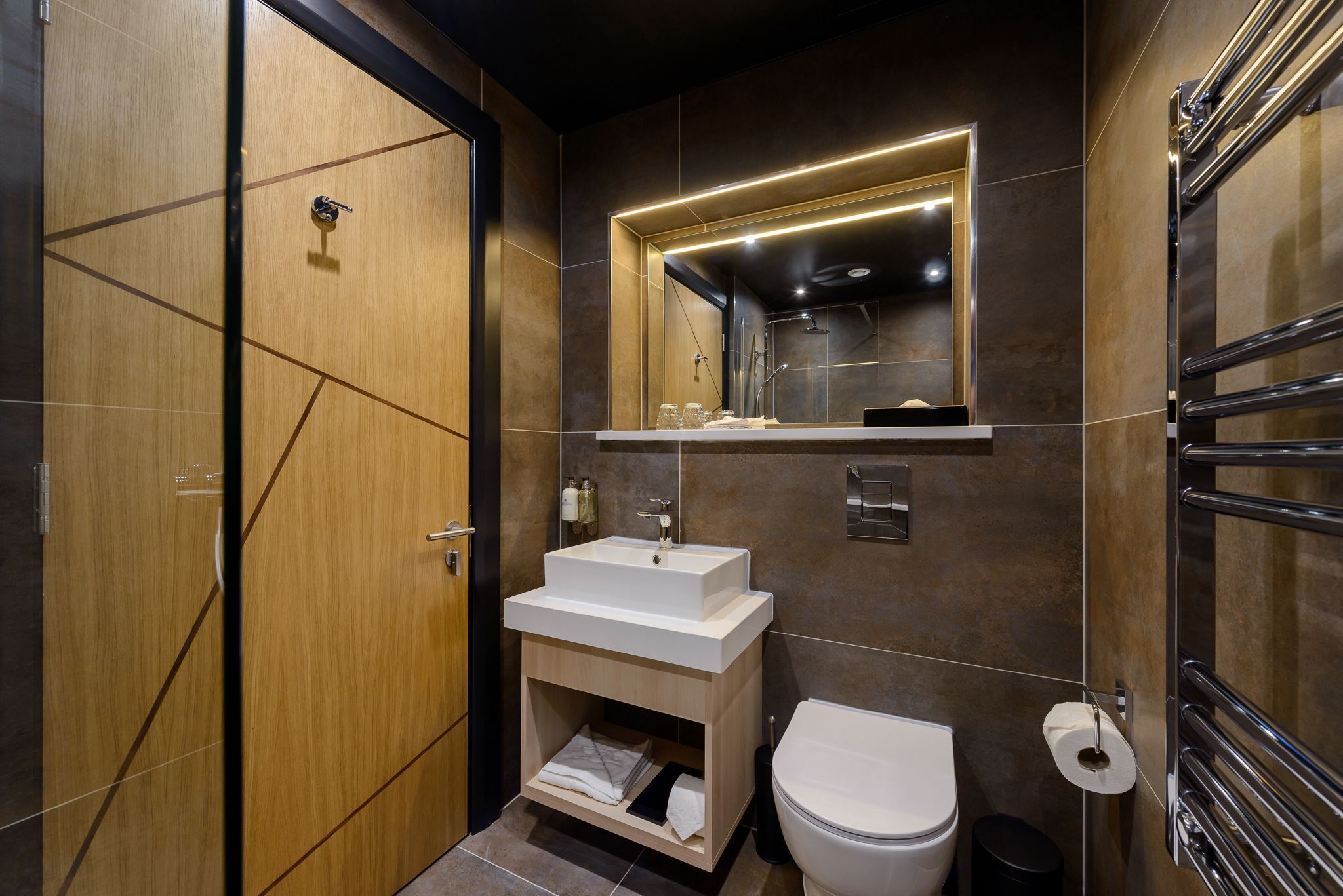 A modern bathroom with a wooden vanity, a white sink, a mirror, and a toilet.