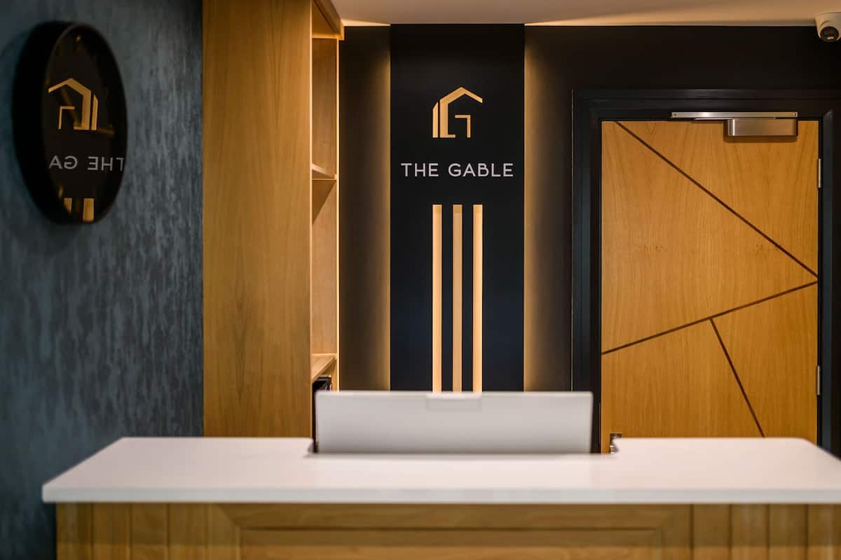 Una mesa de recepción con un letrero que dice 'THE GABLE' y un logotipo encima.