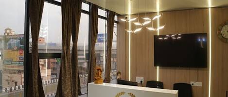 A hotel reception desk with a view of the cityscape through large windows.