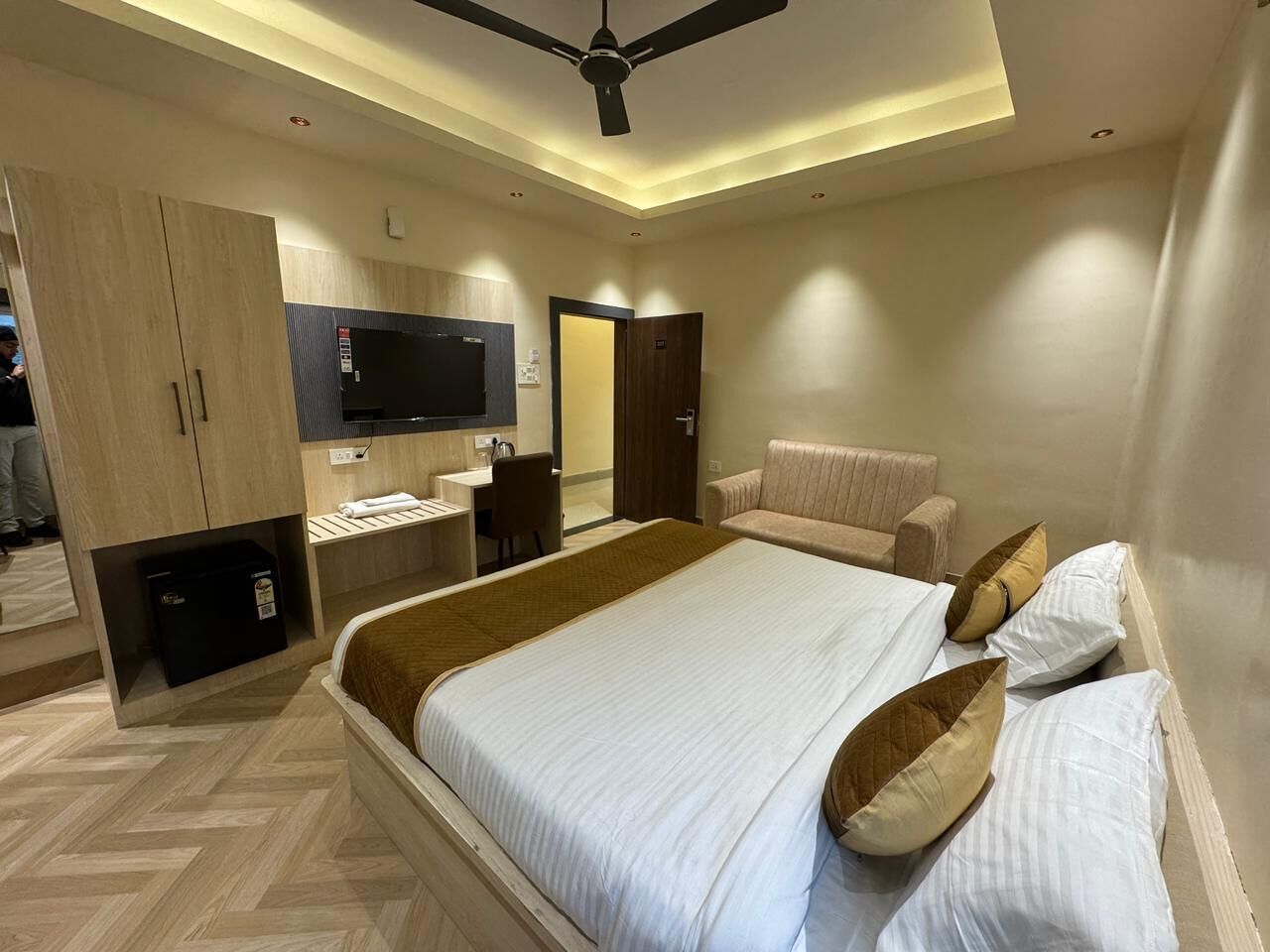 A modern hotel room with a large bed, a desk, and a wardrobe.