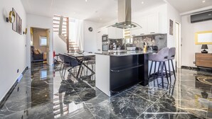 A modern kitchen with a central island, black marble flooring, and a staircase leading to another level. - 1 BR Penthouse for Couples & Families (Pembroke)