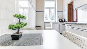 A modern kitchen with white tiles, a potted bonsai tree, and a window with a view of trees. - 2BR Apartment Steps From AKH Center (Vienna)