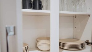 A kitchen with white cabinets and shelves. There are stacks of plates and bowls on the shelves. - Comfort & Convenience in Telford – Cozy 3-Bedroom Home (Telford)