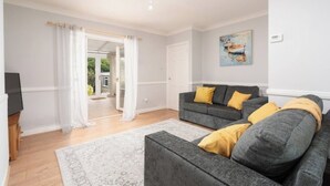 A living room with a grey sofa, a white rug, and a painting on the wall. - Comfort & Convenience in Telford – Cozy 3-Bedroom Home (Telford)