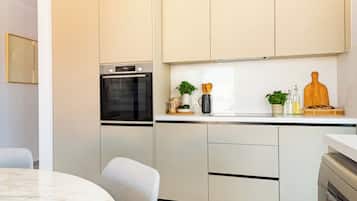 Una cocina moderna con horno integrado, una mesa de comedor y sillas.