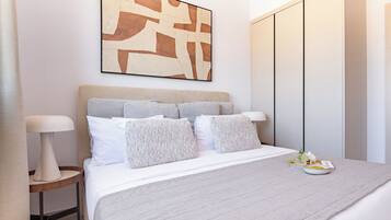 A modern bedroom with a bed, bedside tables, a headboard, a wall-mounted artwork, and a wardrobe.
