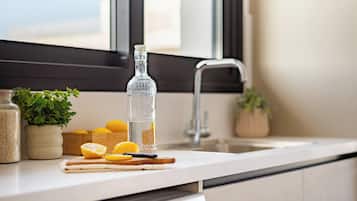 Uma cozinha com pia, tábua de corte com limões, garrafa de vidro e um vaso de planta.