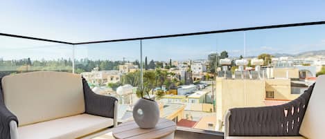 A balcony with two chairs, a small table, and a view of a cityscape.