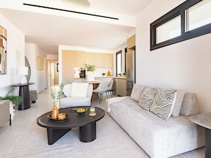 A modern living room with a sofa, coffee table, and a dining area in the background. - Sanders City Boutique - Full Building (Limassol)