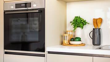 A kitchen with a Bosch oven, a plant, wooden spoons, and jars of ingredients.