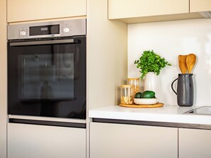 Uma cozinha com forno Bosch, uma planta, colheres de pau e potes com ingredientes.