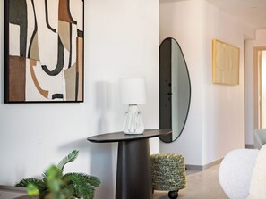 Un interior moderno con una mesa redonda, una lámpara, un espejo y arte abstracto en la pared.