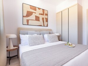 A modern bedroom with a bed, bedside tables, a headboard, a wall-mounted artwork, and a wardrobe. - Sanders City Boutique - Full Building (Limassol)