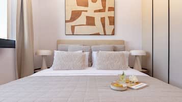 A neatly made bed with a quilted cover, two bedside lamps, and a wall art piece above it.
