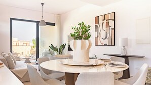 Una sala de estar moderna con una mesa de comedor redonda, asientos cómodos, una planta en maceta y un ventanal con vistas.