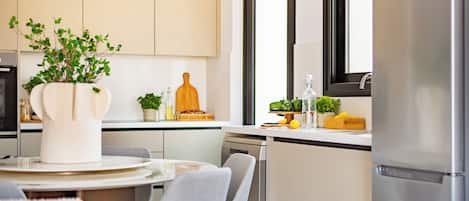 A modern kitchen with a dining area, featuring a round table, chairs, and a potted plant.