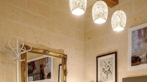 Une chambre à coucher avec un grand lit, une tête de lit en bois, un pouf rond, un miroir et des œuvres d’art accrochées aux murs.