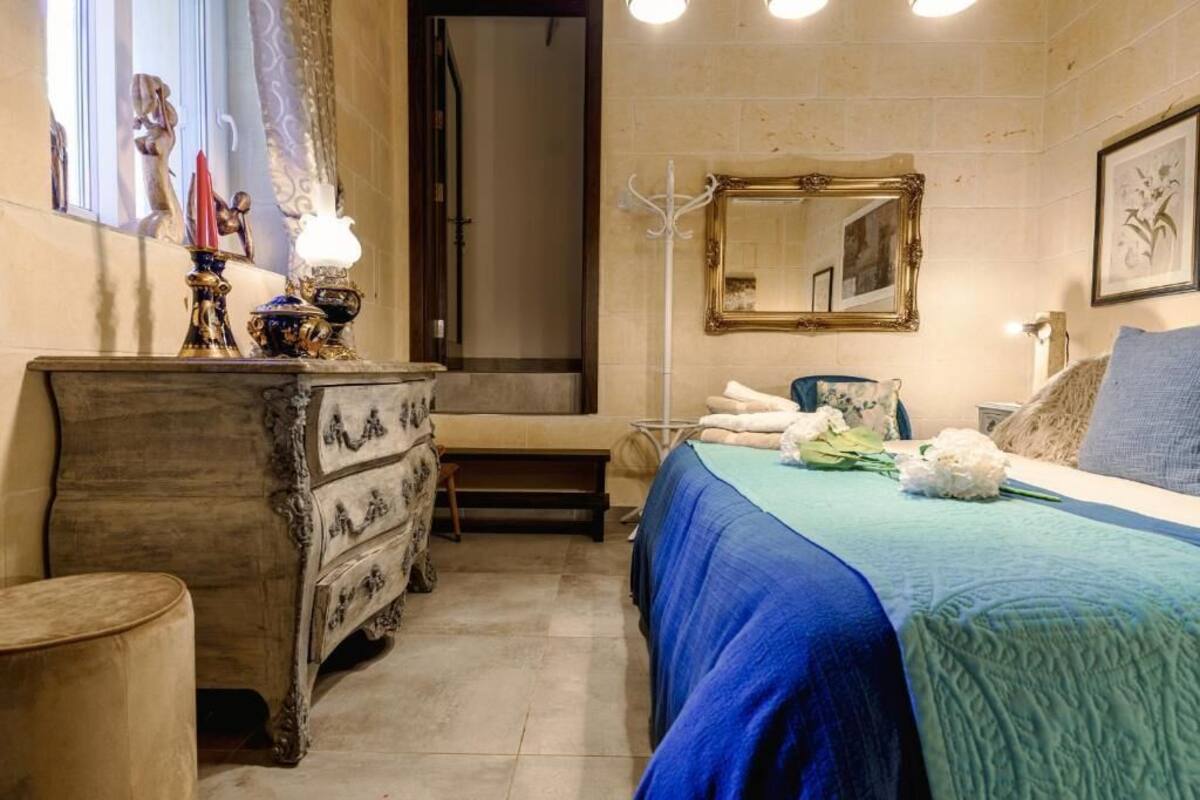 Une chambre à coucher avec un lit, une commode, un miroir et une fenêtre avec des rideaux.