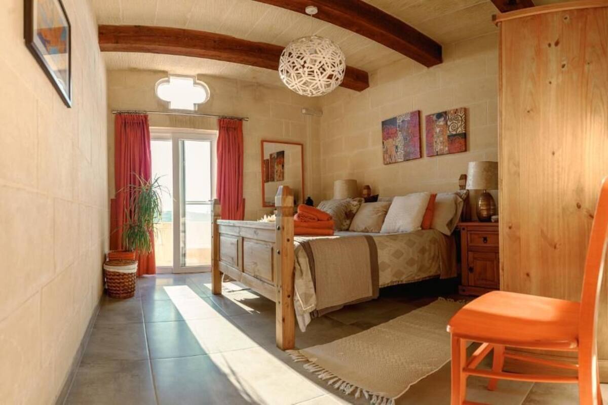 Une chambre à coucher avec un lit, une chaise, une armoire en bois et une grande fenêtre.