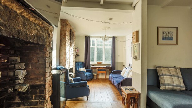 Un salon chaleureux avec une cheminée, un canapé bleu et un plancher en bois.