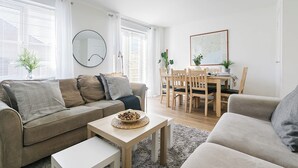 Ein modernes Wohnzimmer mit einer Couch, einem Couchtisch und einem Essbereich mit Tisch und Stühlen.