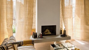 Un salon moderne avec une cheminée, des canapés à rayures et une table basse en verre.