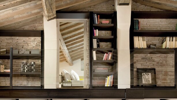 Un loft spacieux avec des poutres apparentes, un escalier et un coin salon confortable agrémenté de coussins à rayures.