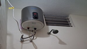 En vandvarmervarmeteknisk installation på væggen med kontrolpanel, ventil og vandudløb.