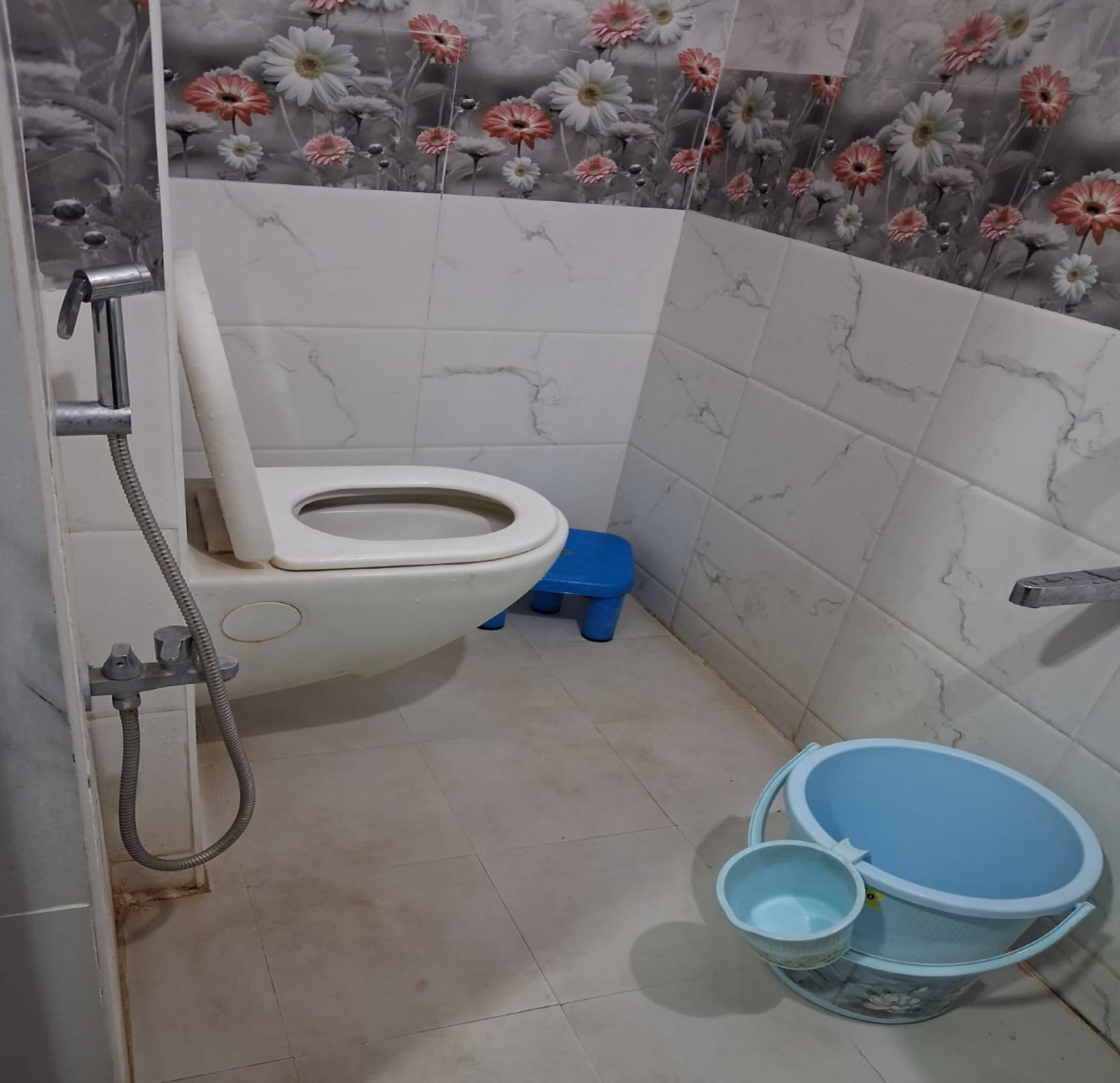 Egy fürdőszoba, amelyben WC, zuhanyzó és kék műanyag mosdókagyló található.