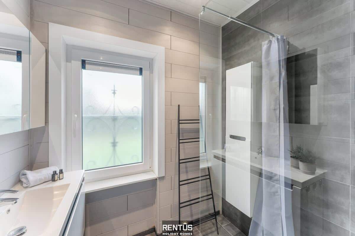 A modern bathroom with a window, a towel rack, and a shower curtain.