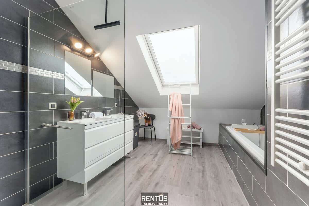 A modern bathroom with a skylight, a white vanity, and a towel rack.