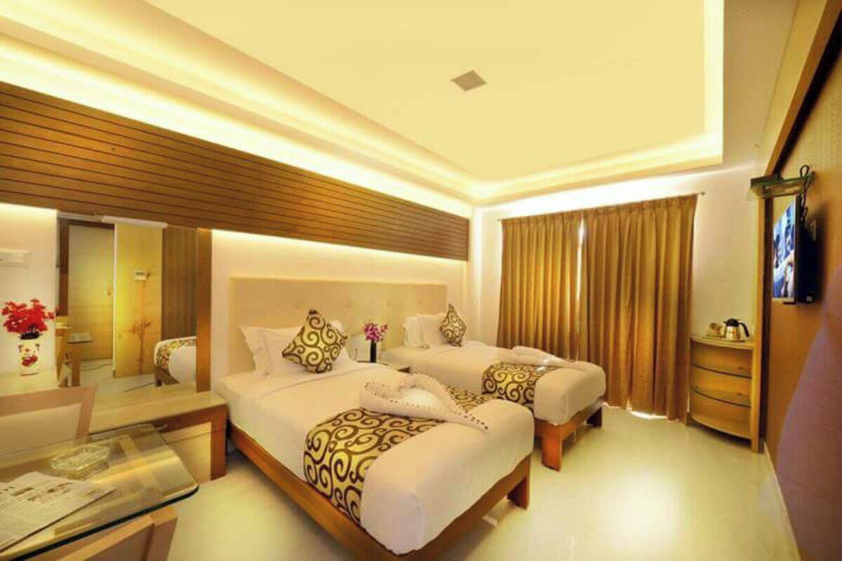 A hotel room with two beds, a glass table, a bedside table, and a mirror.