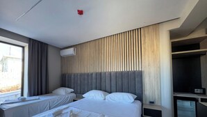 A hotel room with two beds, a wooden slat headboard, an air conditioning unit, a television, and a window with curtains. - Aeris Sol Ksamil - Free Parking - Pool (Ksamil)