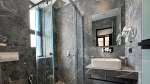 A modern bathroom with a glass shower enclosure, a white sink, and a marble-tiled floor. - Aeris Sol Ksamil - Free Parking - Pool (Ksamil)