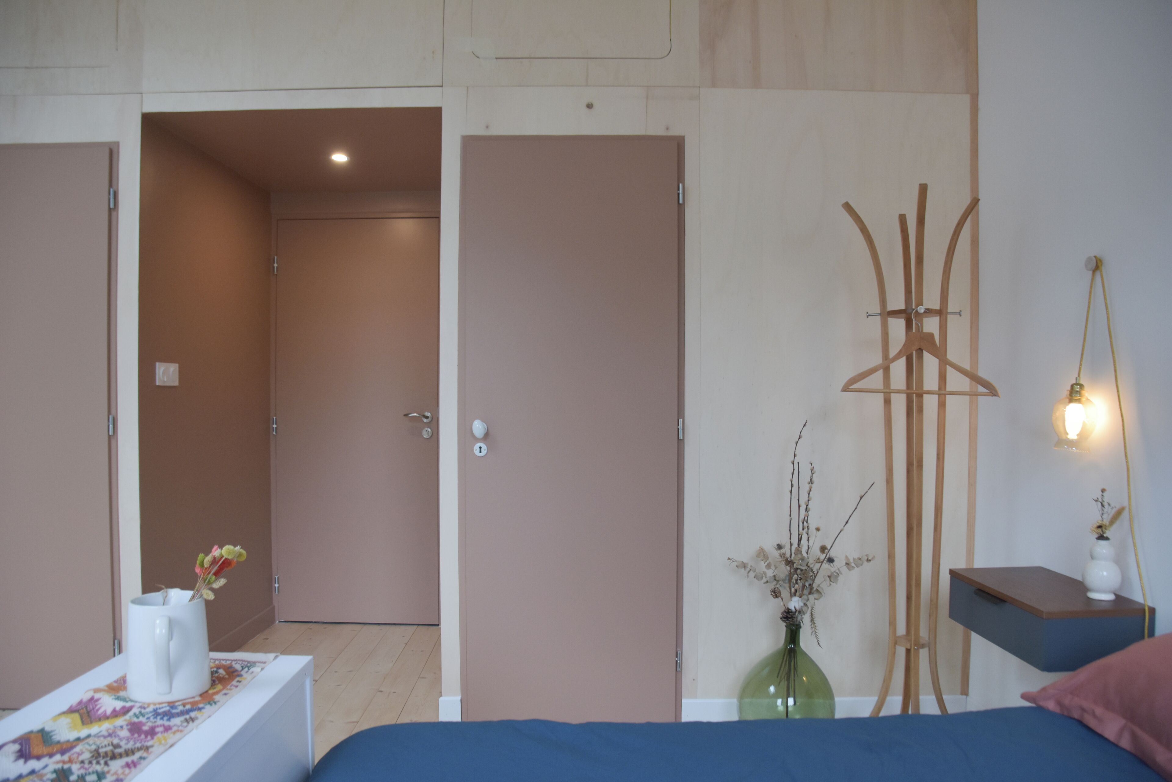Un dormitorio con cama, mesita de noche, cómoda y perchero en la pared.