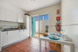 Une cuisine avec des meubles blancs, un évier et une table où sont disposés des aliments pour le petit-déjeuner.