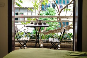 A balcony with a table set for tea, two chairs, and a view of greenery and buildings. - Seréne - Old Quarter Centre Hotel Ha Noi (Hanoi)
