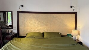A neatly made bed with a green bedspread, a bedside lamp, and a nightstand with a lamp. - Seréne - Old Quarter Centre Hotel Ha Noi (Hanoi)
