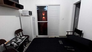 Une petite pièce compacte comprenant un lit, un bureau avec un jeu d’échecs, un four à micro-ondes et un placard avec une porte coulissante.