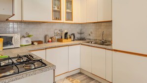 Et moderne køkken med hvide skabe, en granitbordplade, en gasovn, en vask og en brødrister.