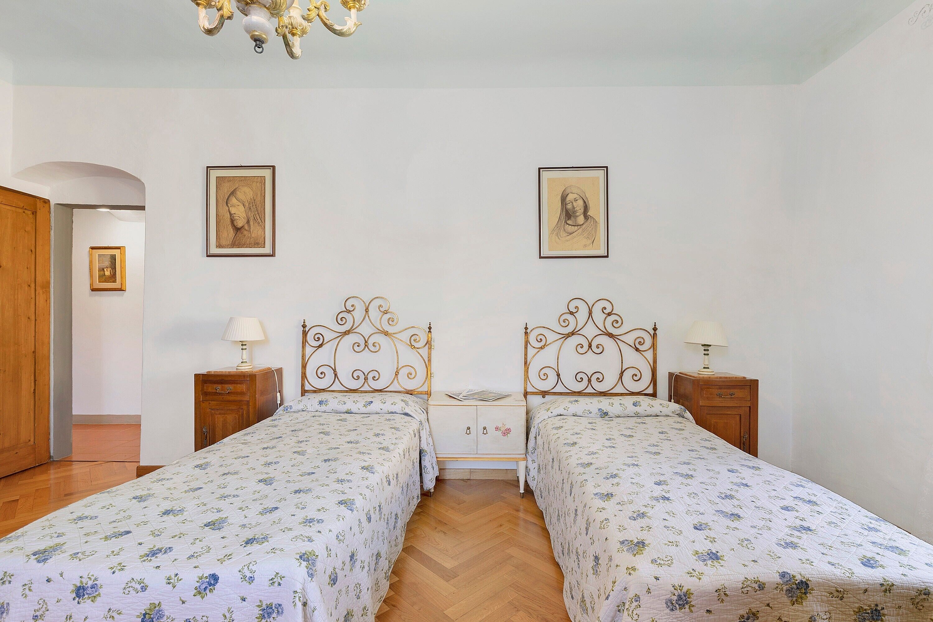 Une chambre avec deux lits, des têtes de lit en bois, une armoire en bois et une petite table de chevet avec une lampe.