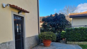 A courtyard with a stone floor, a potted plant, and a building with a door and window. - Casa Relax in the Countryside (Pomino)