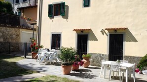 A building with multiple windows, a paved courtyard, outdoor seating, and potted plants. - Casa Relax in the Countryside (Pomino)