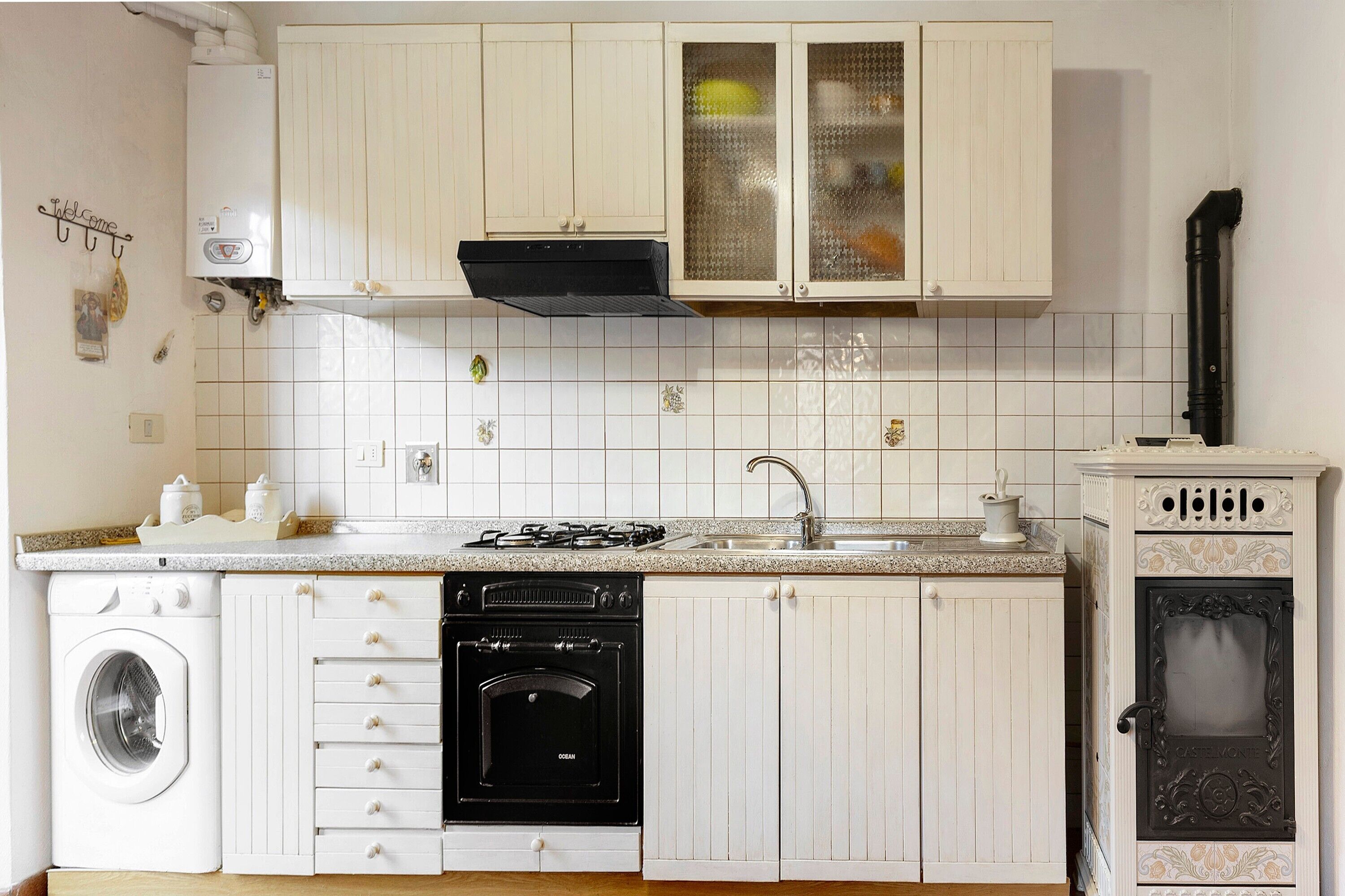 A kitchen with white cabinets, a stove, a dishwasher, and a built-in oven.