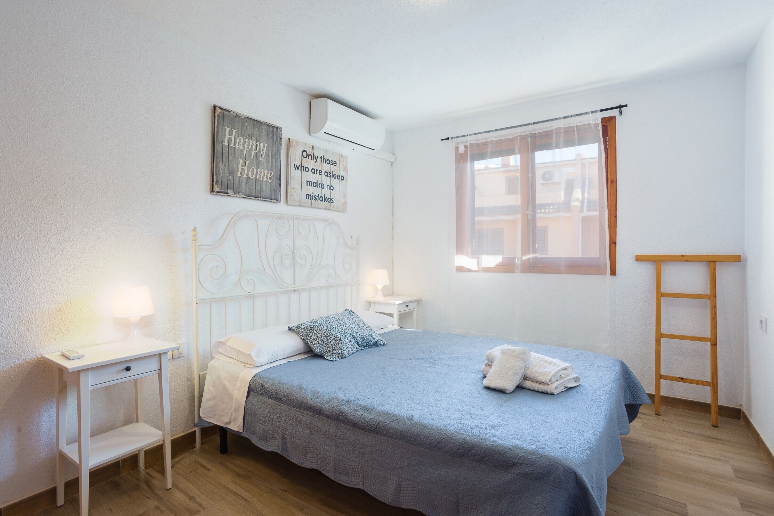 Une chambre à coucher comprenant un lit, des tables de chevet, une fenêtre avec des rideaux et des éléments décoratifs sur les murs.