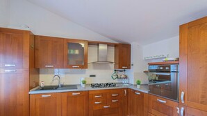 Une cuisine avec des meubles de rangement en bois, une cuisinière à gaz, un évier et un four.